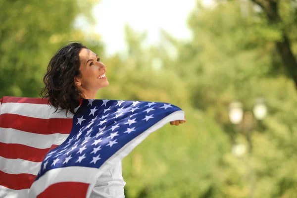 Happy young woman with American flag in park on sunny day — Stock Photo, Image