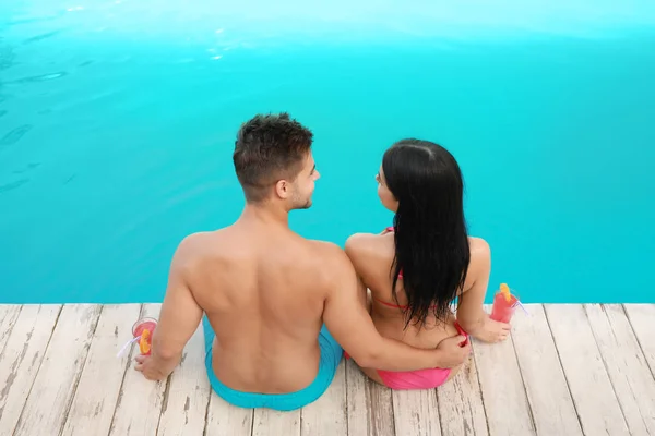 Mujer en bikini con novio cerca de piscina al aire libre. Pareja joven — Foto de Stock