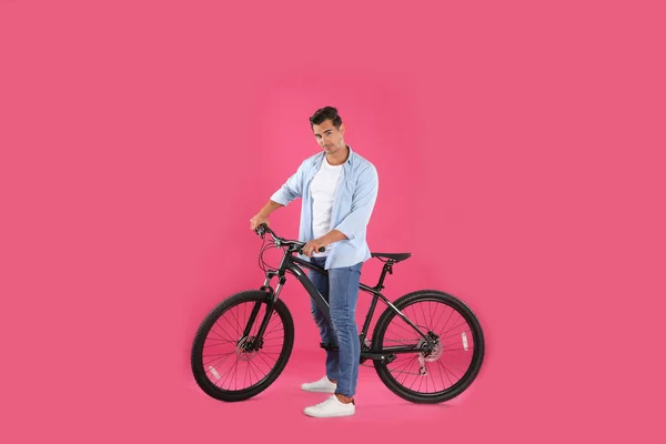 Красивый молодой человек с современным велосипедом на розовом фоне — стоковое фото