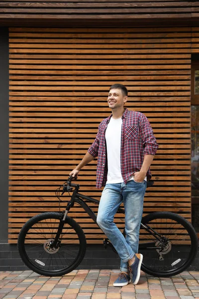 Красивий чоловік з сучасним велосипедом біля будівлі на відкритому повітрі — стокове фото