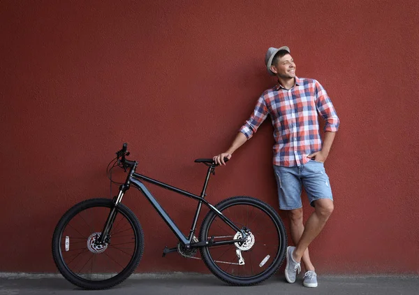 Pohledný muž s moderním bicykl poblíž Rudé zdi venku — Stock fotografie