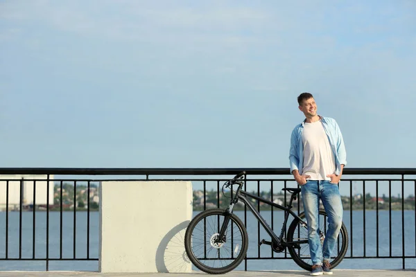 Bărbat frumos cu bicicletă modernă lângă râu — Fotografie, imagine de stoc