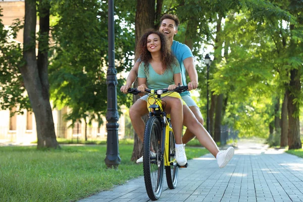 Feliz joven pareja montando bicicleta en la calle de la ciudad — Foto de Stock