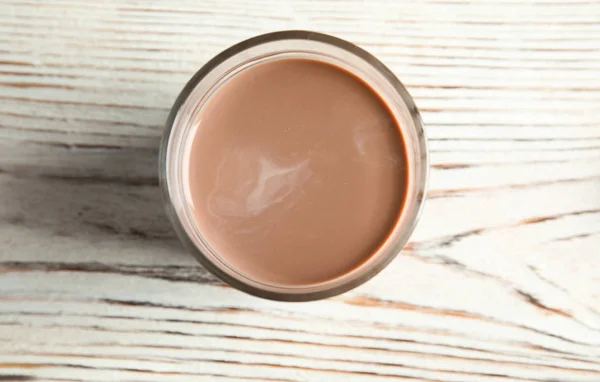 Glas smakelijke chocolademelk op houten achtergrond, bovenaanzicht. Zuivel drank — Stockfoto