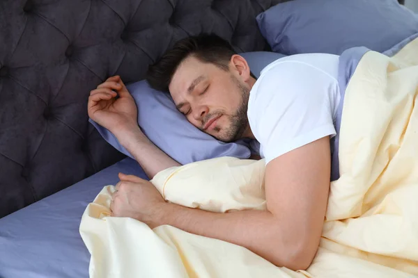 Un bel homme dormant sur un oreiller à la maison. Au lit. — Photo