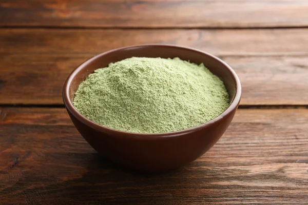 Bowl of wheat grass powder on wooden table