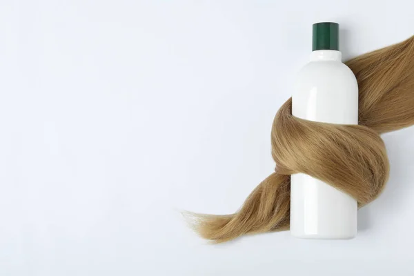 Botella de champú envuelto en mechón de pelo aislado en blanco, vista superior. Productos cosméticos naturales — Foto de Stock