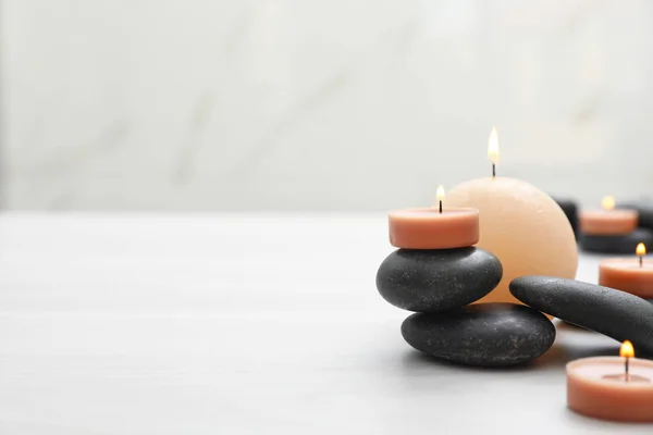 Komposition mit Wellness-Steinen und Kerzen auf weißem Tisch. Raum für Text — Stockfoto