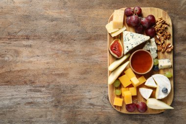 Ahşap arka plan üzerinde lezzetli peynir ve aperatifler kurulu ile Düz yatıyordu kompozisyon. Metin için alan