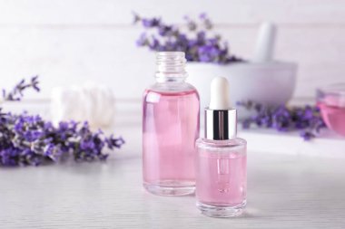 Beyaz ahşap masada gerekli yağ ve lavanta çiçekleri.