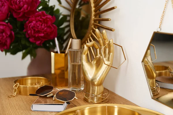 白い壁の近くのドレッシングテーブルに金のアクセサリーと花と組成物 — ストック写真