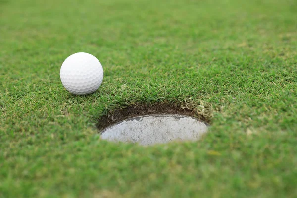 Yeşil sahada deliğin yakınında golf topu — Stok fotoğraf