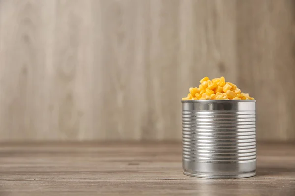 Open tin can of sweet corn on wooden table, space for text — Stock Photo, Image