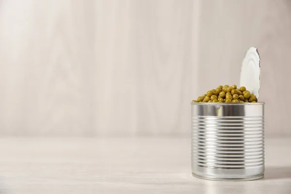 Open tin can of green peas on light table, space for text