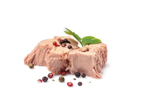 Kawałki tuńczyka w puszkach z pietruszką i pieprzem na białym tle — Zdjęcie stockowe