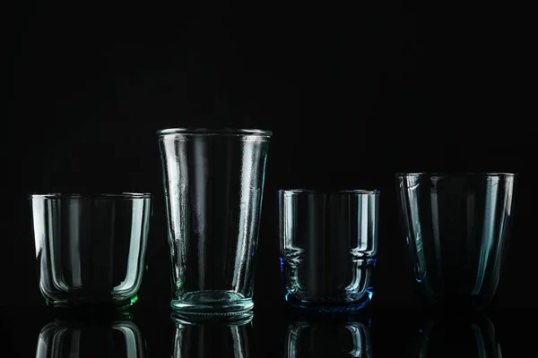 Set aus verschiedenen bunten leeren Gläsern auf schwarzem Hintergrund — Stockfoto