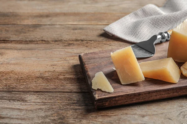 Σανίδα με κομμένο τυρί παρμεζάνα σε ξύλινο τραπέζι. Χώρος για κείμενο — Φωτογραφία Αρχείου
