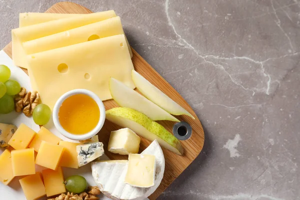 Placa com diferentes tipos de queijo delicioso e lanches no fundo de mármore, vista superior. Espaço para texto — Fotografia de Stock