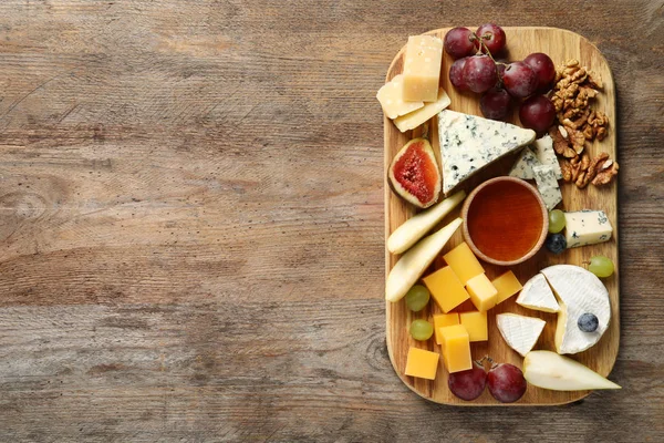 Ahşap arka plan üzerinde lezzetli peynir ve aperatifler kurulu ile Düz yatıyordu kompozisyon. Metin için alan