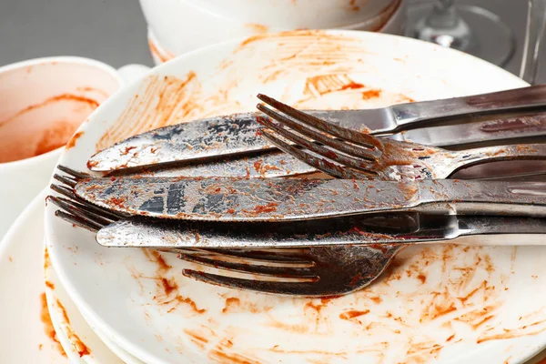 Stack of dirty dishes with cutlery, closeup