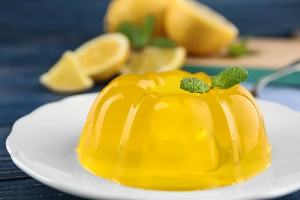 Plate with lemon jelly and mint on wooden table, closeup