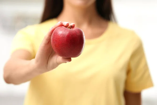 Mujer sosteniendo manzana roja fresca en el interior, primer plano — Foto de Stock