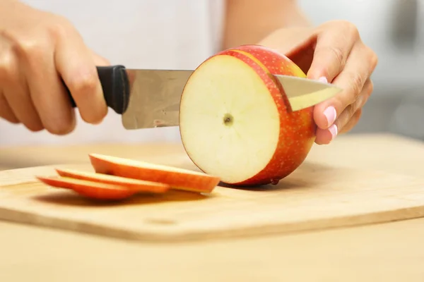 Mujer cortando manzana fresca en la mesa de madera en el interior, primer plano — Foto de Stock