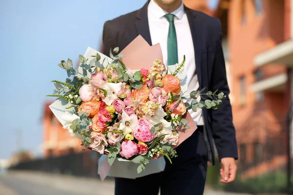 Homem em terno elegante com lindo buquê de flores na rua, vista de close-up — Fotografia de Stock