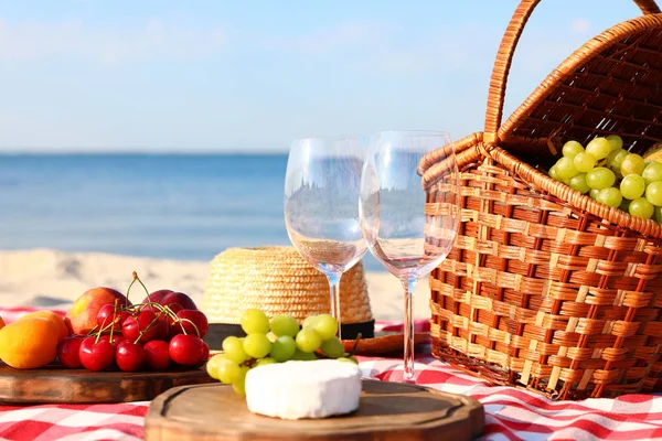 Güneşli plajda piknik sepeti ve ürünleri ile damalı battaniye. Metin alanı