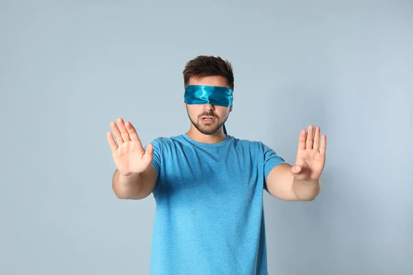 Young man with light blue blindfold on grey background — Stock Photo, Image