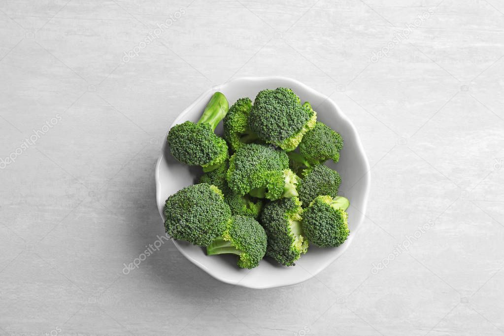 Bowl of fresh broccoli on light grey table, top view