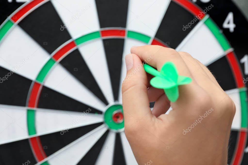 Woman with green arrow near dart board, closeup