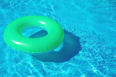 Yeşil şişme halka güneşli bir günde yüzme havuzunda yüzen. Metin için alan