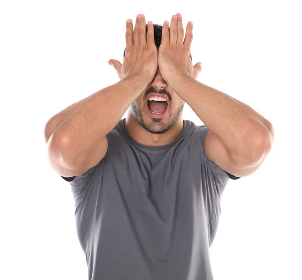 Young man being blinded and covering eyes with hands on white background — Stock Photo, Image