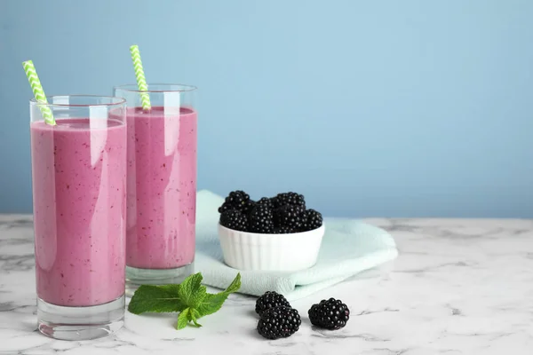 Delicioso batido de mora en vasos sobre mesa de mármol. Espacio para texto —  Fotos de Stock