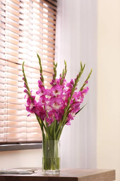 Vas dengan indah bunga gladiolus merah muda di atas meja kayu di kamar, ruang untuk teks — Stok Foto