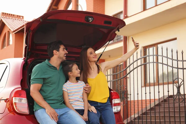 Familia feliz tomando selfie cerca de coche en la calle — Foto de Stock