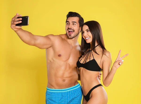 Joven pareja atractiva en ropa de playa tomando selfie sobre fondo amarillo — Foto de Stock