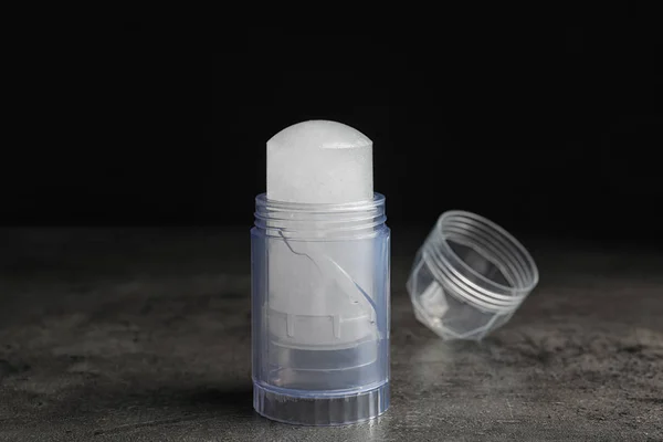 Naturalny dezodorant z kryształu Alum i czapka na szarym stole na czarnym tle — Zdjęcie stockowe