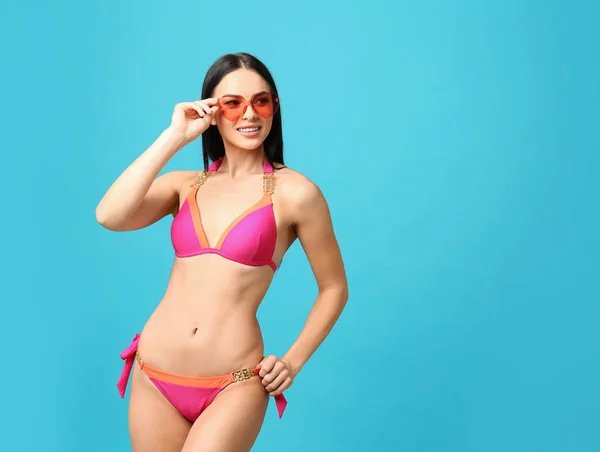 Hermosa mujer joven en bikini elegante con gafas de sol sobre fondo azul claro. Espacio para texto —  Fotos de Stock