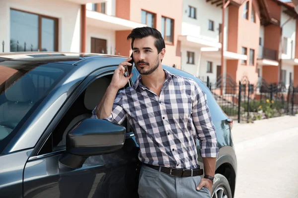 매력적인 젊은 남자 는 야외 에서 고급 자동차 근처 전화로 이야기 — 스톡 사진