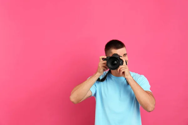 Mladý profesionální fotograf fotografi na růžovém pozadí. Místo pro text — Stock fotografie