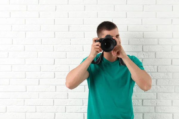 Fiatal profi fotós vesz kép közelében téglafal. Szóköz a szöveghez — Stock Fotó