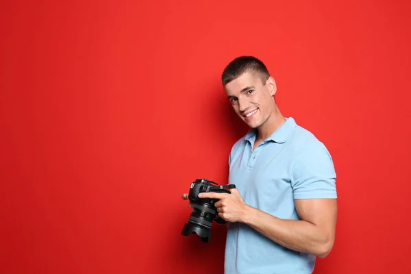 Jovem fotógrafo com câmera profissional em fundo vermelho. Espaço para texto — Fotografia de Stock