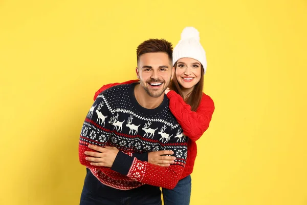 Casal usando camisolas de Natal no fundo amarelo — Fotografia de Stock