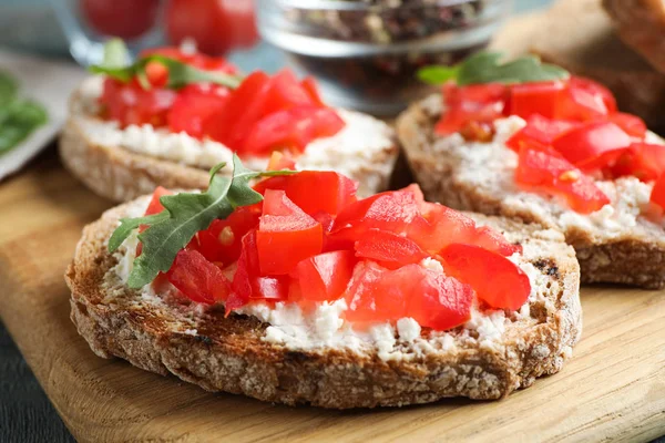 Tablero de madera con deliciosos bruschettas de tomate en la mesa, primer plano —  Fotos de Stock