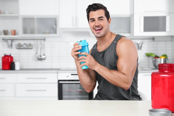 Hombre atlético joven con batido de proteínas en polvo en la cocina, espacio para el texto —  Fotos de Stock