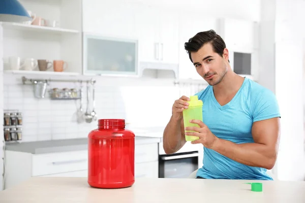 Jovem atlético preparando batido de proteína na cozinha, espaço para texto — Fotografia de Stock