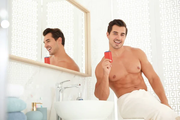 Joven guapo con desodorante en el baño — Foto de Stock