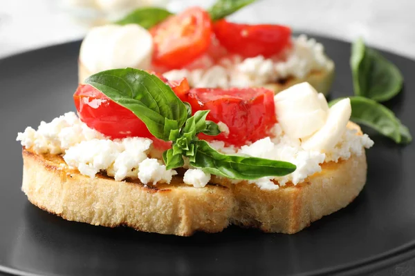 Tasty fresh tomato bruschettas on black plate, closeup — Stock Photo, Image